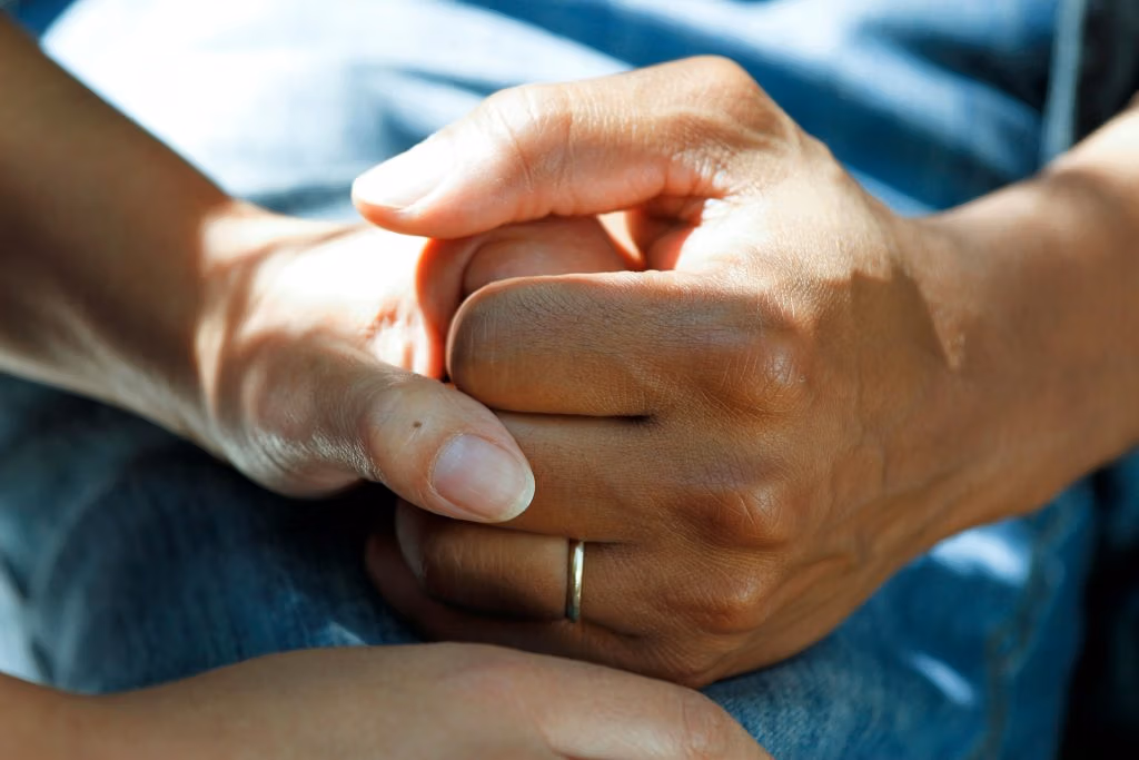 Career holing the hand of a care home resident